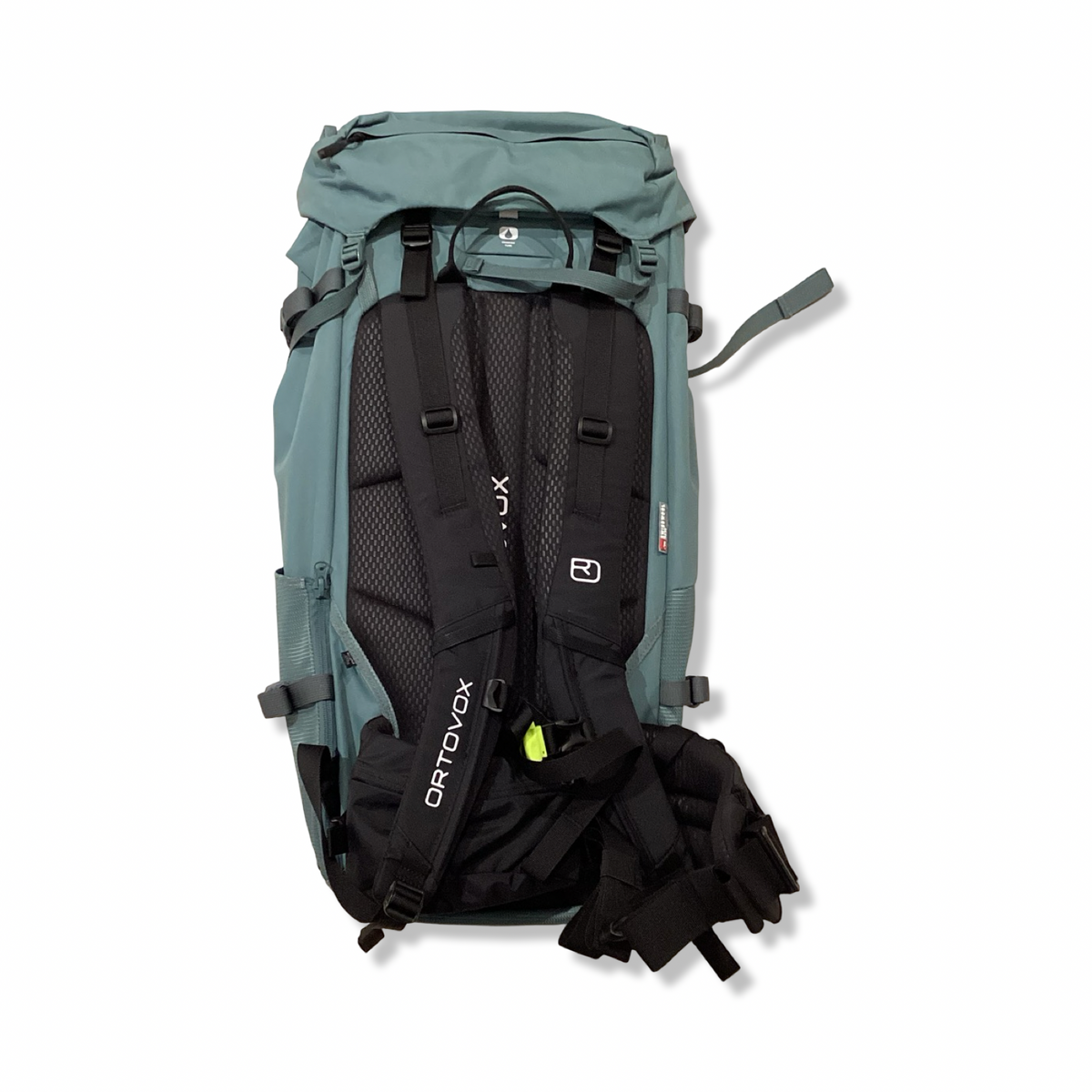 Baksidan av en blågrön Ortovox Peak 45 ryggsäck för unisex med svarta axelremmar, visad mot en vit bakgrund.