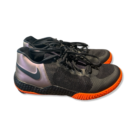 Svarta Nike-löparskor för dam med orange yttersula och snörning, fotograferade från sidan mot vit bakgrund.
