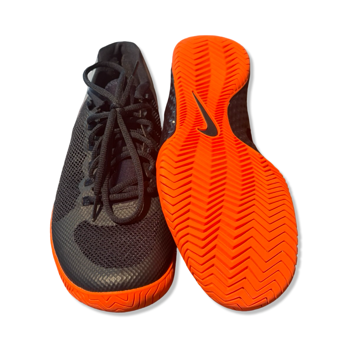 Svarta Nike-löparskor för dam med snörning och orange yttersula där den ena skon visar undersidan.