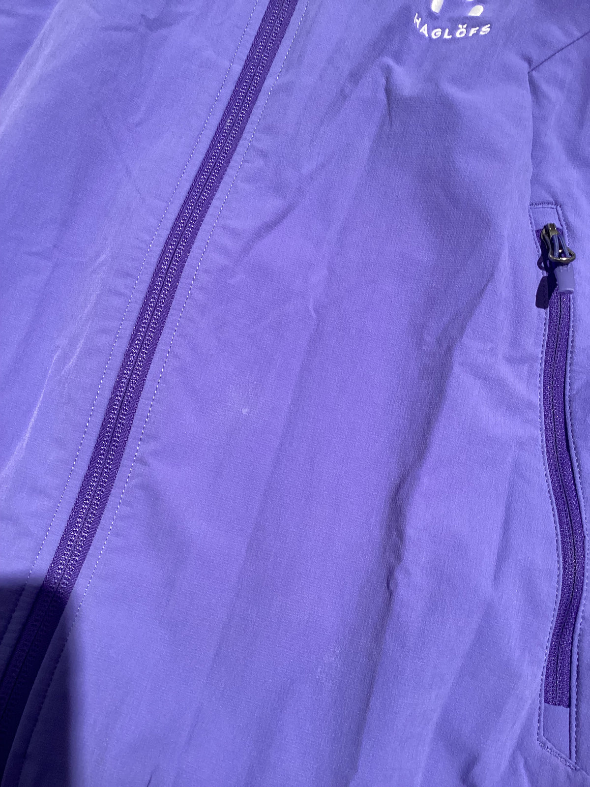 Close-up of a purple Haglöfs softshell jacket featuring a zipper and chest pocket.