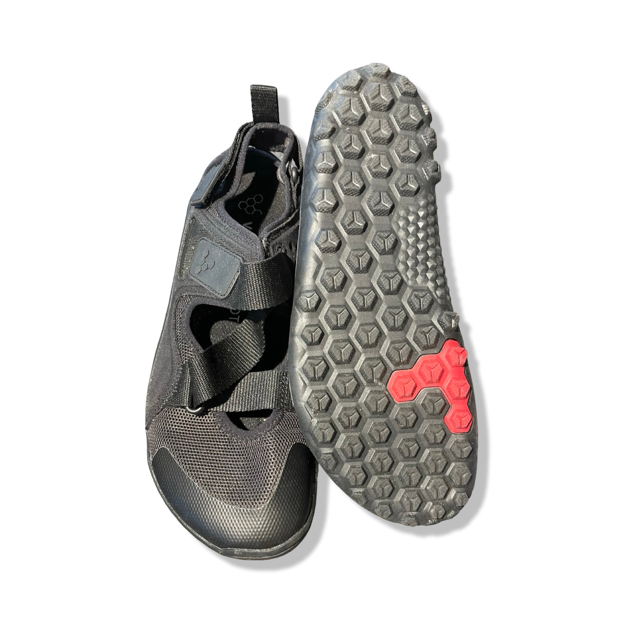 Svarta Vivobarefoot-sandaler mot vit bakgrund, där en sandal visas uppifrån och den andra visar den mönstrade sulan.
