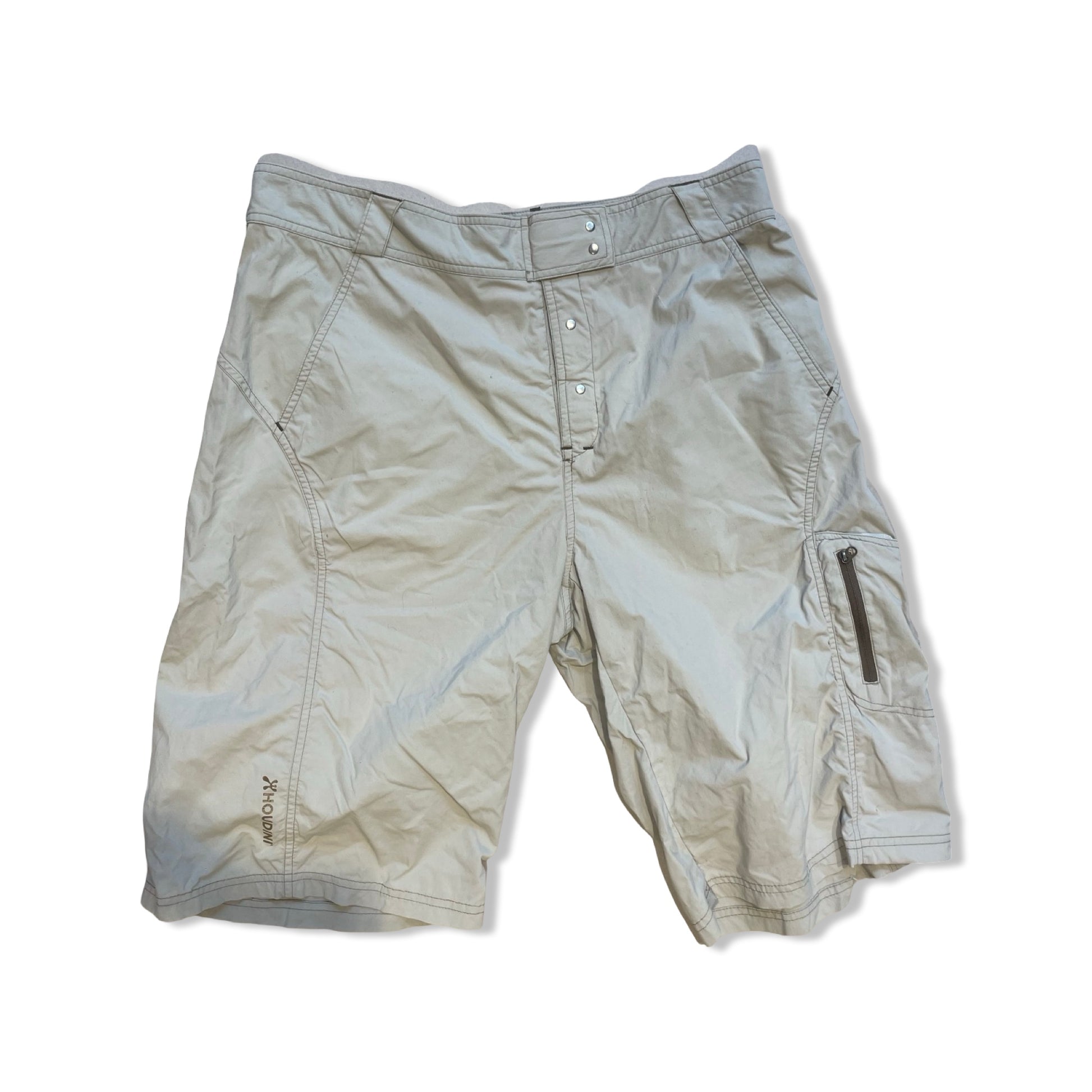 Beige Houdini funktionsshorts för dam, fotograferade platt mot en vit bakgrund.