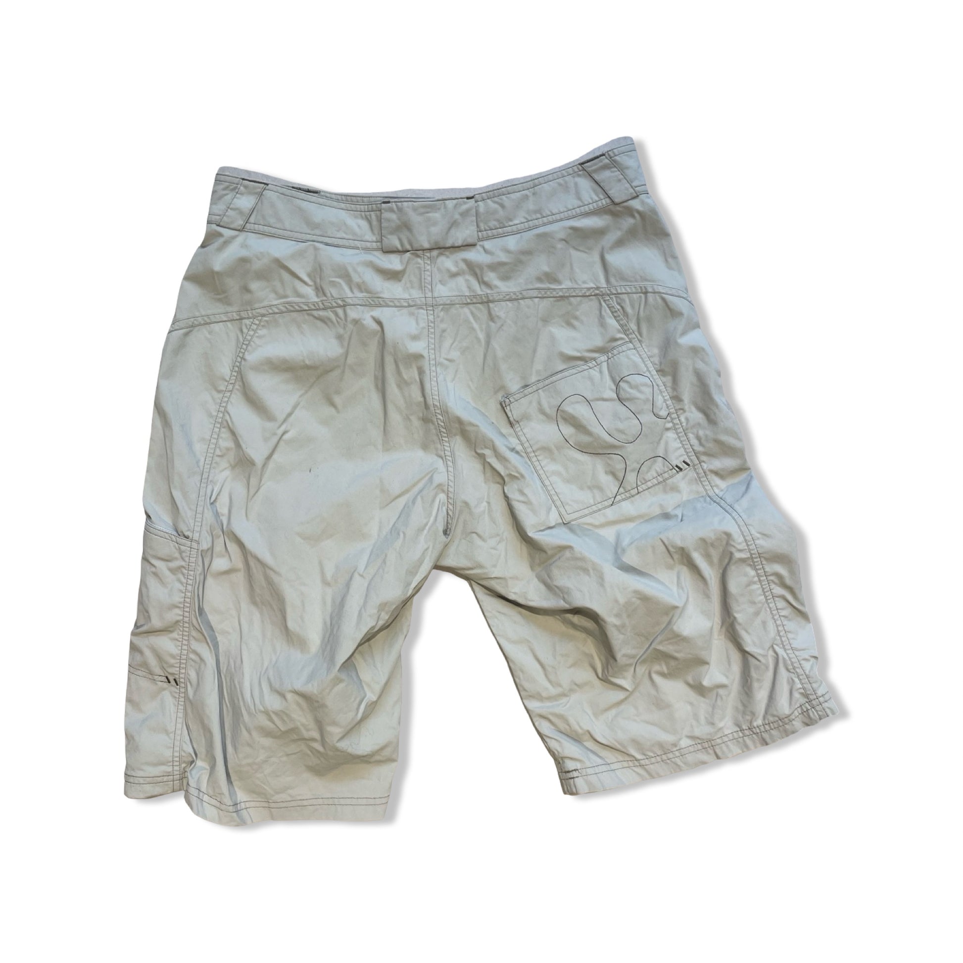 Beige Houdini funktionsshorts för dam sedda bakifrån med broderad logotyp på bakfickan mot vit bakgrund.