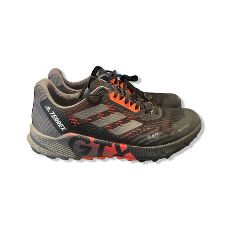Adidas Terrex Gore-Tex löparskor för dam i svart, orange och grått, fotograferade från sidan mot en vit bakgrund.