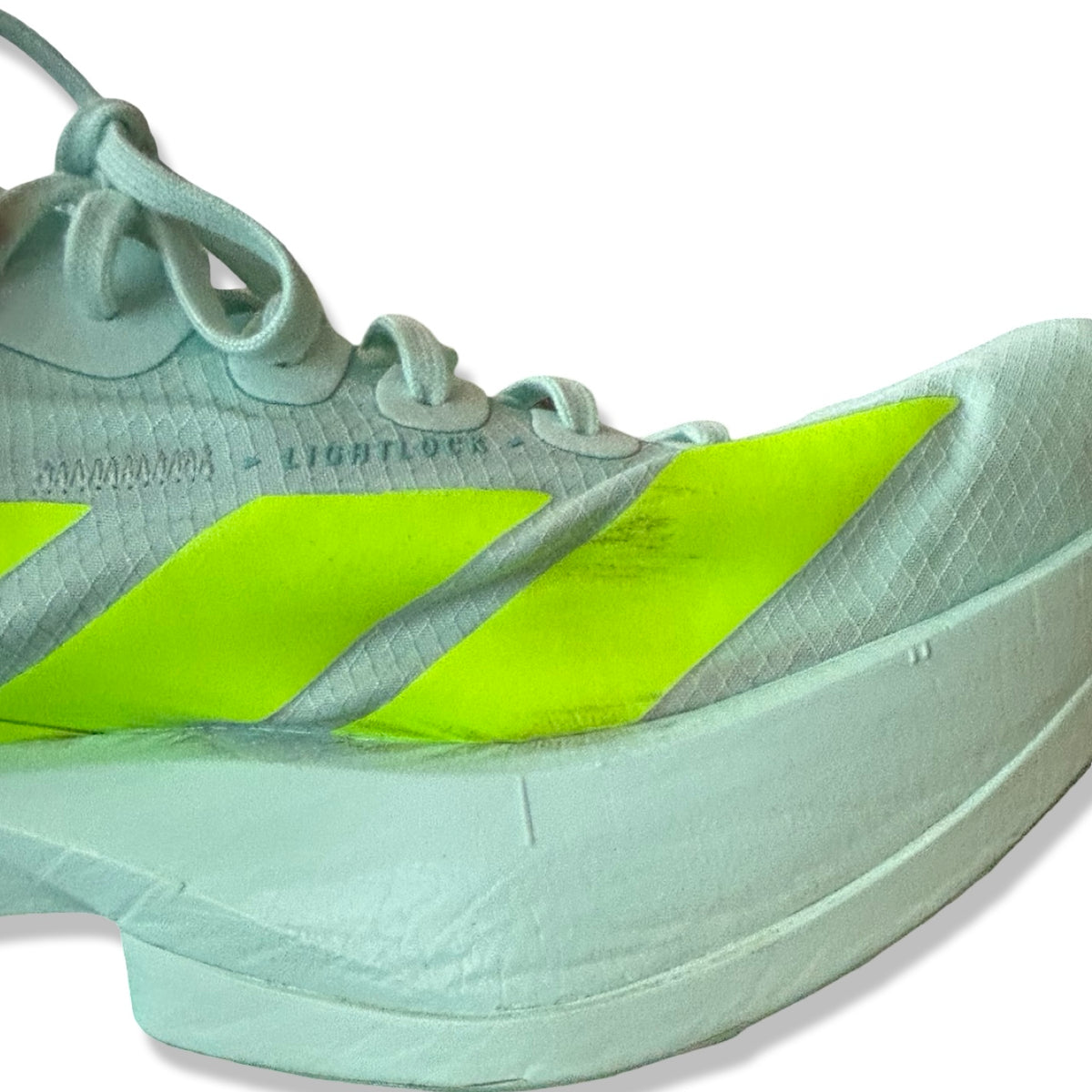 Närbild på fläckar på de turkosa löparskorna Adidas Adizero Adios Pro 4 för dam mot en vit bakgrund.