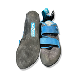 Black and blue women's climbing shoes from Scarpa Origin with velcro straps, shown with sole and upper against a white background.