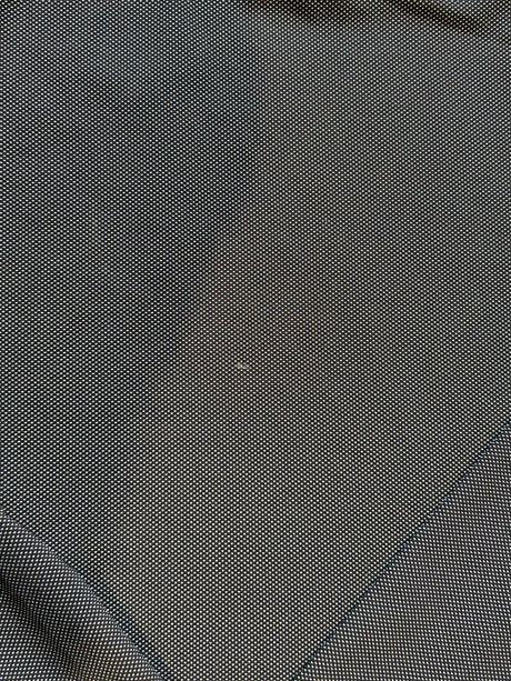 Närbild på det grå och svarta funktionstygsmaterialet med en liten fläck på Peak Performance funktionströja för herr.