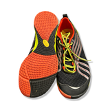 Black Merrell training shoes with orange outsole and yellow shoelaces, photographed from underneath and front against a white background.