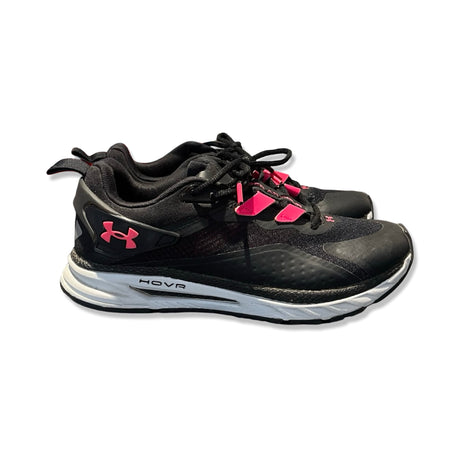 Svarta Under Armour HOVR löparskor för dam med rosa detaljer och vit sula, sedda från sidan mot en vit bakgrund.