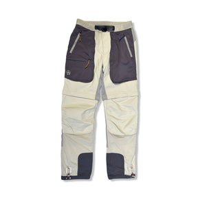 Beige funktionsbyxor från Peak Performance för dam med mörka fickdetaljer, fotograferade framifrån mot en ljus bakgrund.