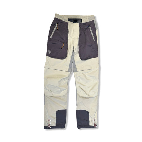 Beige funktionsbyxor från Peak Performance för dam med mörka fickdetaljer, fotograferade framifrån mot en ljus bakgrund.