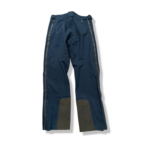 Back view of a blue Fjällräven men's Bergtagen Eco-Shell ski pants with side zippers against a white background.