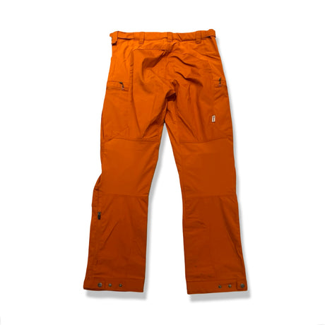 Baksidan av ett par orange vandringsbyxor för dam från Re-Adventure, fotograferade mot en vit bakgrund.