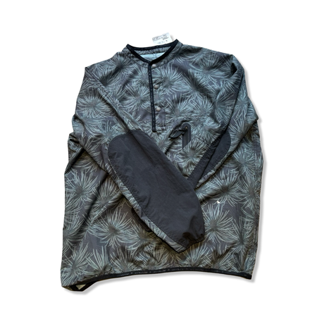 Gray-green patterned And Wander training jacket with black elbow patches against a white background.