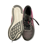 A pair of black and pink Asics women's training shoes where one shoe shows the outsole and the other is seen from the front.