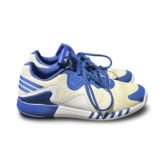 Tennissko Adidas Y-3 Adizero Roland Garos för dam i vitt och blått, fotograferade från sidan mot en vit bakgrund.