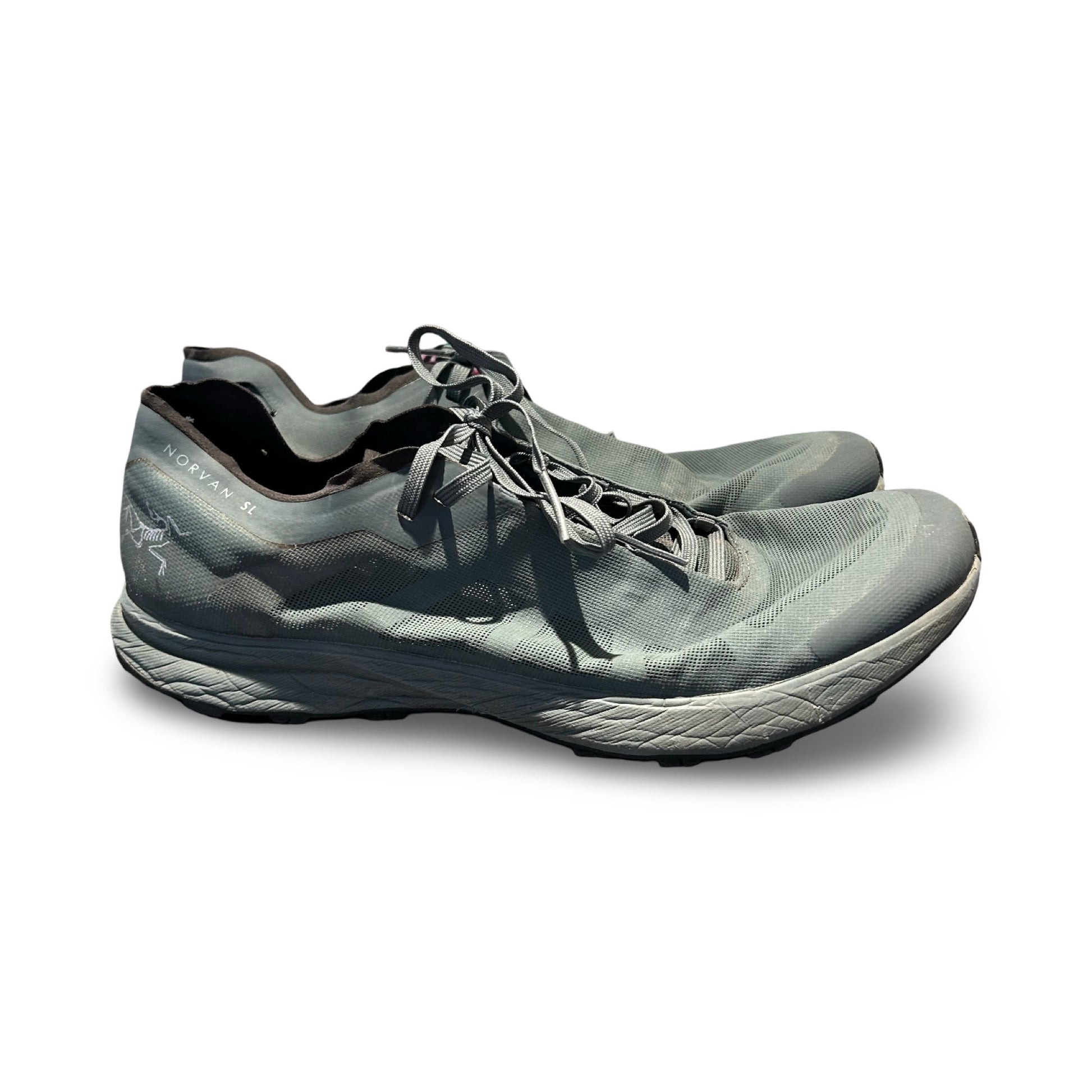 Arc'teryx Norvan SL löparskor i grått, fotograferade från sidan mot en vit bakgrund.