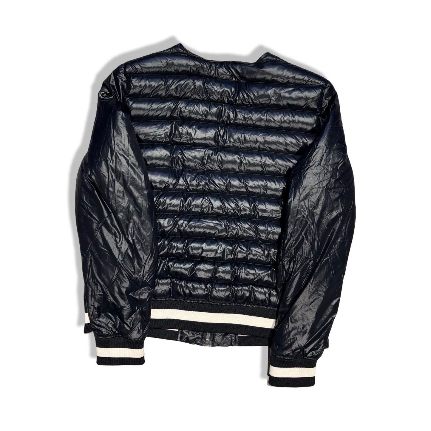 Baksidan av en svart, glansig dunjacka i bombermodell från Peak Performance för dam. Jackan har vita ränder på muddarna och är fotograferad mot en vit bakgrund.