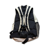 Beige and black Dakine backpack with padded shoulder straps and chest strap, back view against a white background.