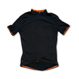 Women's Triban black short-sleeved cycling jersey with orange accents and zipper, front view on white background.