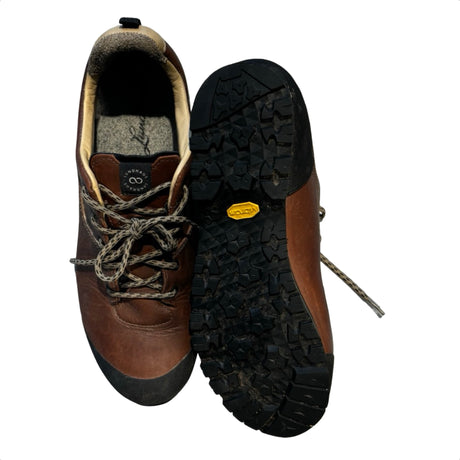 Bruna Lundhags Stuore Low vandringsskor för herr i läder, med ena skons Vibram-sula synlig mot vit bakgrund.