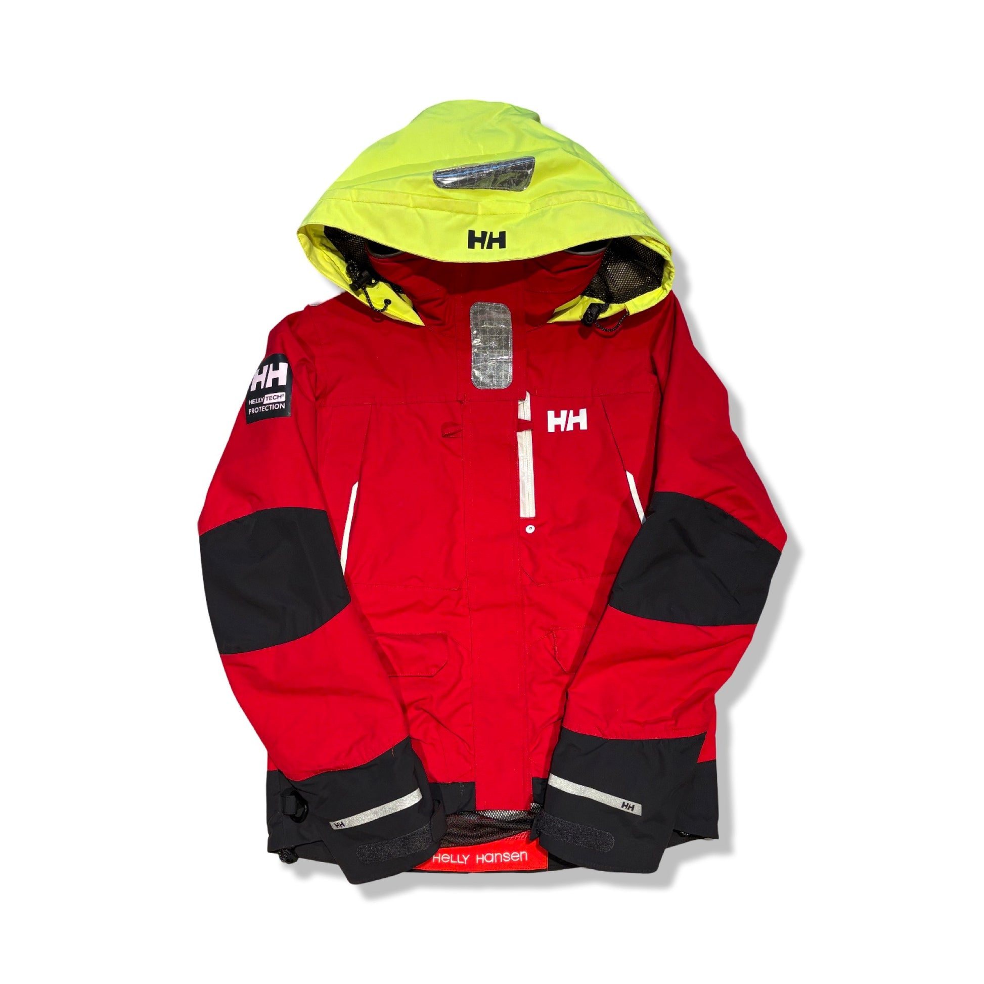 Helly Hansen seglarjacka för dam i rött med svarta detaljer och en neongul huva, fotograferad platt mot en vit bakgrund.