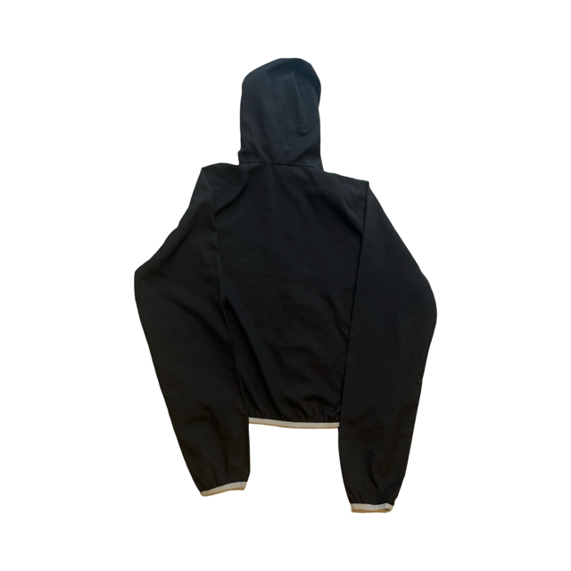 Svart Peak Performance windstopperjacka för dam sedd bakifrån, med luva och ljusa elastiska detaljer.