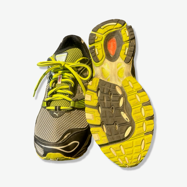 Men's Puma running shoes in neon green and grey, featuring a top view and the textured rubber sole.