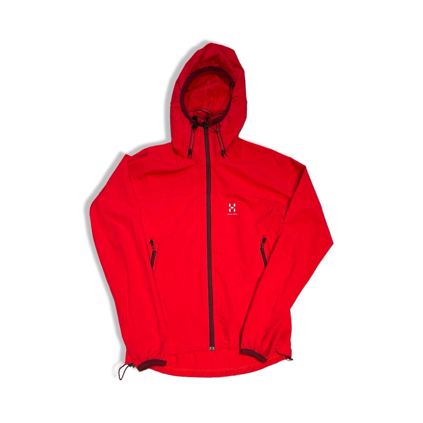 Haglöfs softshelljacka för dam i rött. Jackan har huva och heldragen dragkedja och är fotograferad platt mot en vit bakgrund.