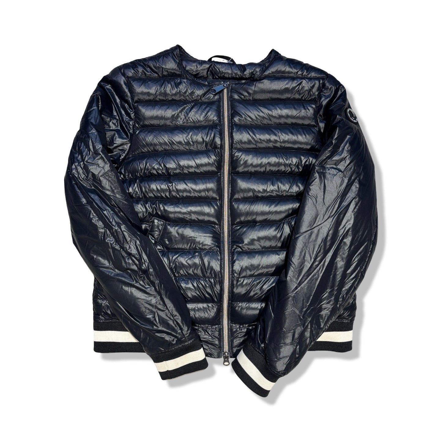 Svart, glansig dunjacka från Peak Performance för dam med randiga muddar, fotograferad framifrån mot en vit bakgrund.