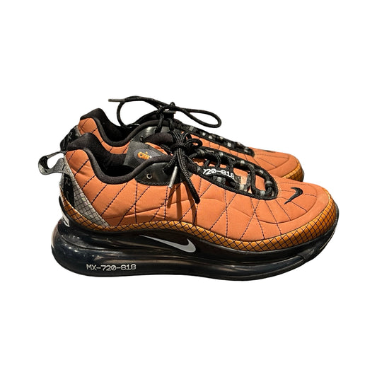 Ett par Nike Air Max 720-818 sneakers för dam i metallisk koppar och svart. Skorna har en quiltad ovandel och en tjock svart sula, fotograferade från sidan mot en vit bakgrund.