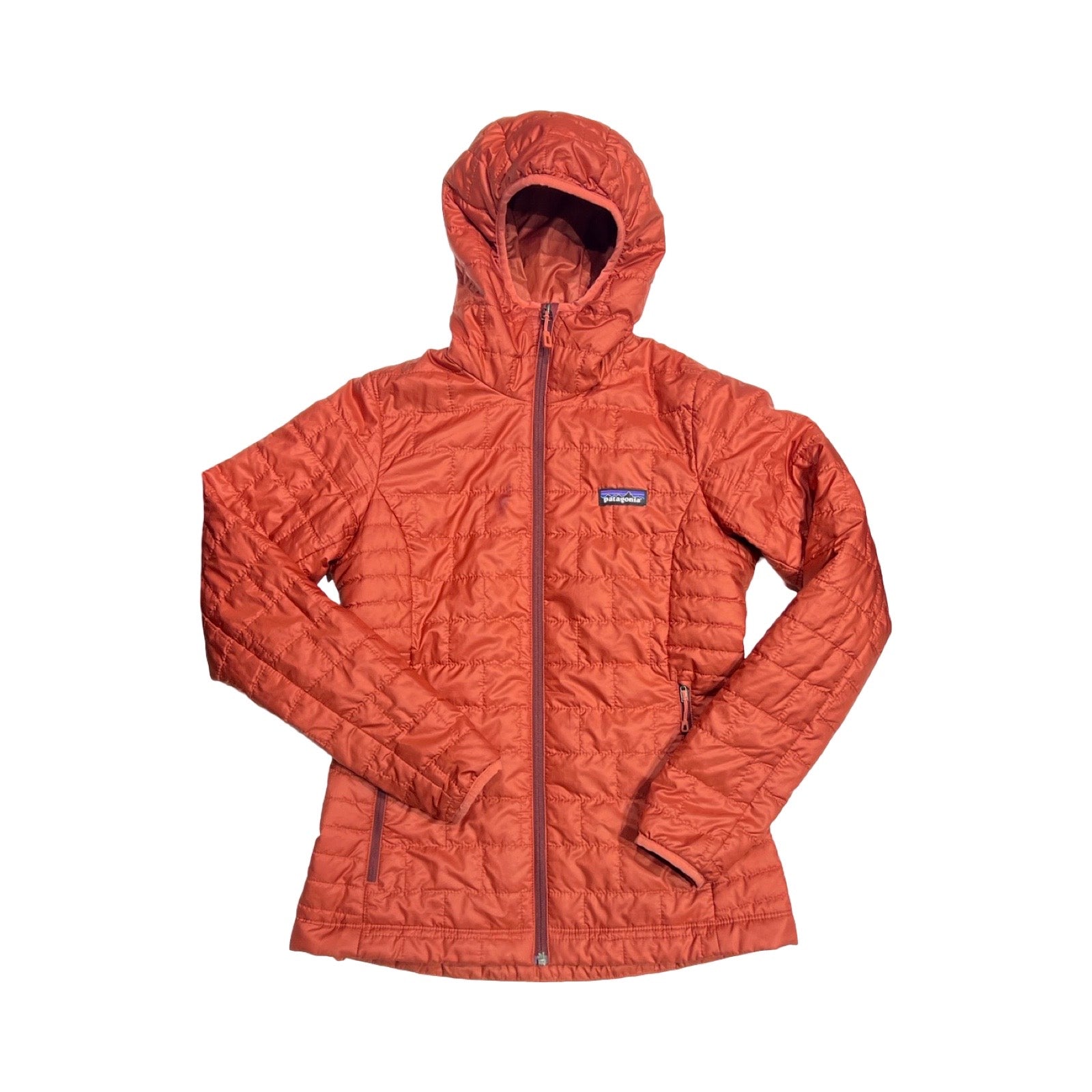 Patagonia Nano Puff syntetjacka för dam i rostrött. Jackan har huva och heldragen dragkedja och är fotograferad framifrån mot en vit bakgrund.