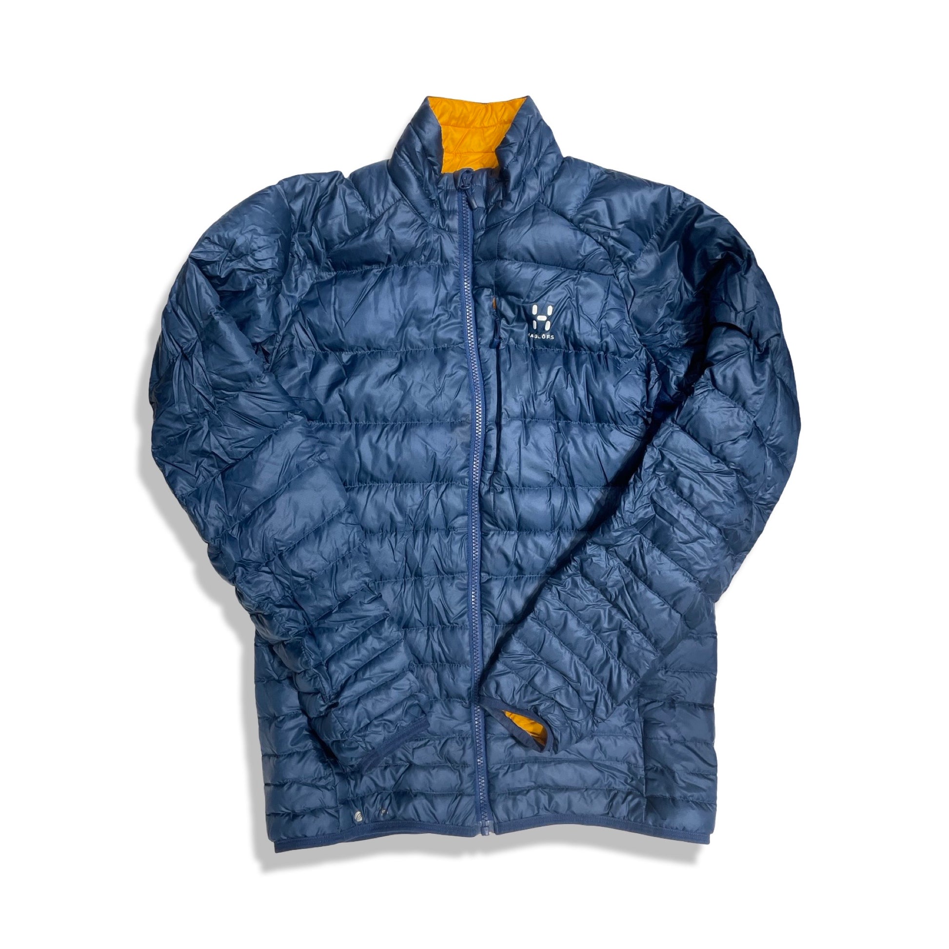 Dunjacka Haglöfs Essens III för herr i blått med orange foder, fotograferad framifrån mot en vit bakgrund.