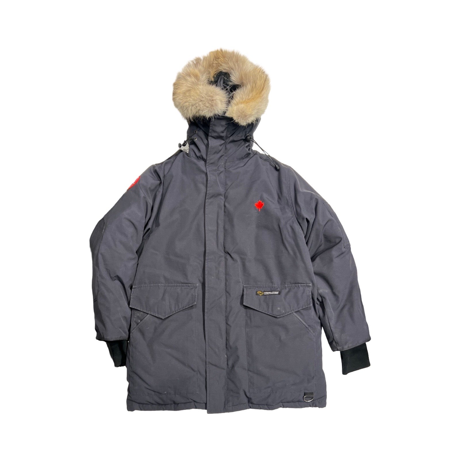 Canada Goose Heli Arctic dunjacka för herr i svart. Jackan har huva med pälskrage och heldragen dragkedja och är fotograferad platt mot en vit bakgrund.