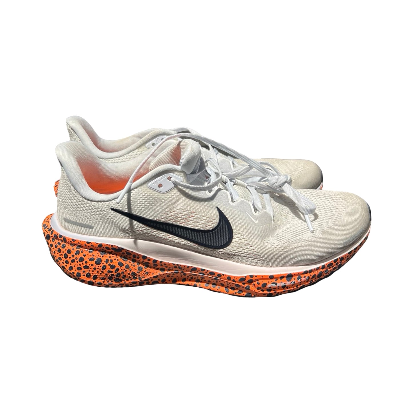 Nike ZoomX träningsskor för herr i ljusgrått. Skorna har en orange sula med svarta prickar och svart logotyp, och är fotograferade snett framifrån mot en vit bakgrund.