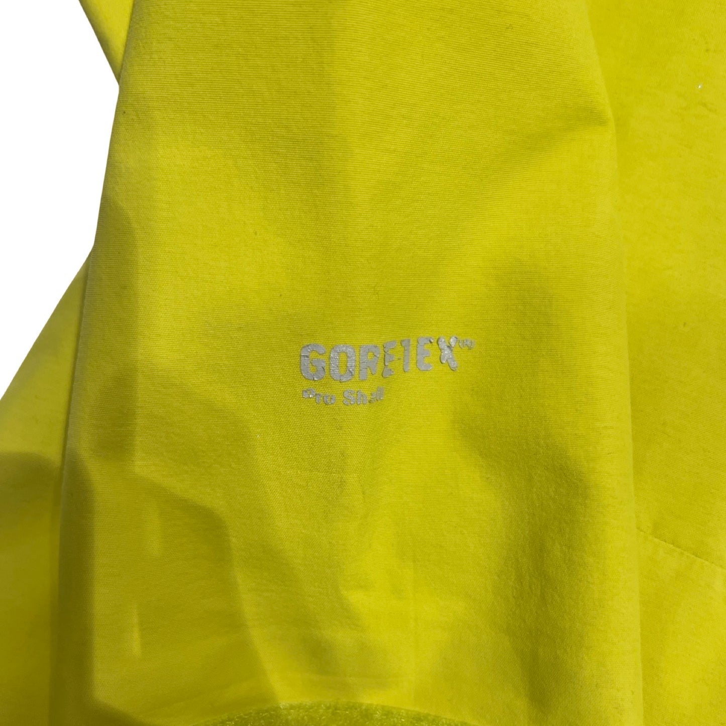 Närbild på slitage på Gore-Tex-loggan på ärmen av den gulgröna The North Face Point Five skaljackan för dam.