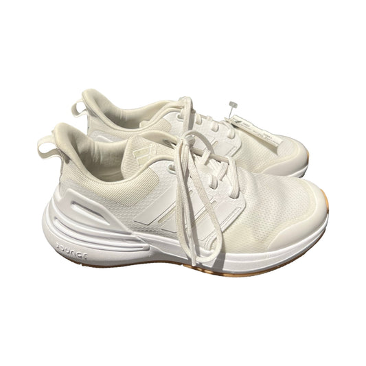 Ett par vita Adidas träningsskor för barn, fotograferade från sidan mot en vit bakgrund.