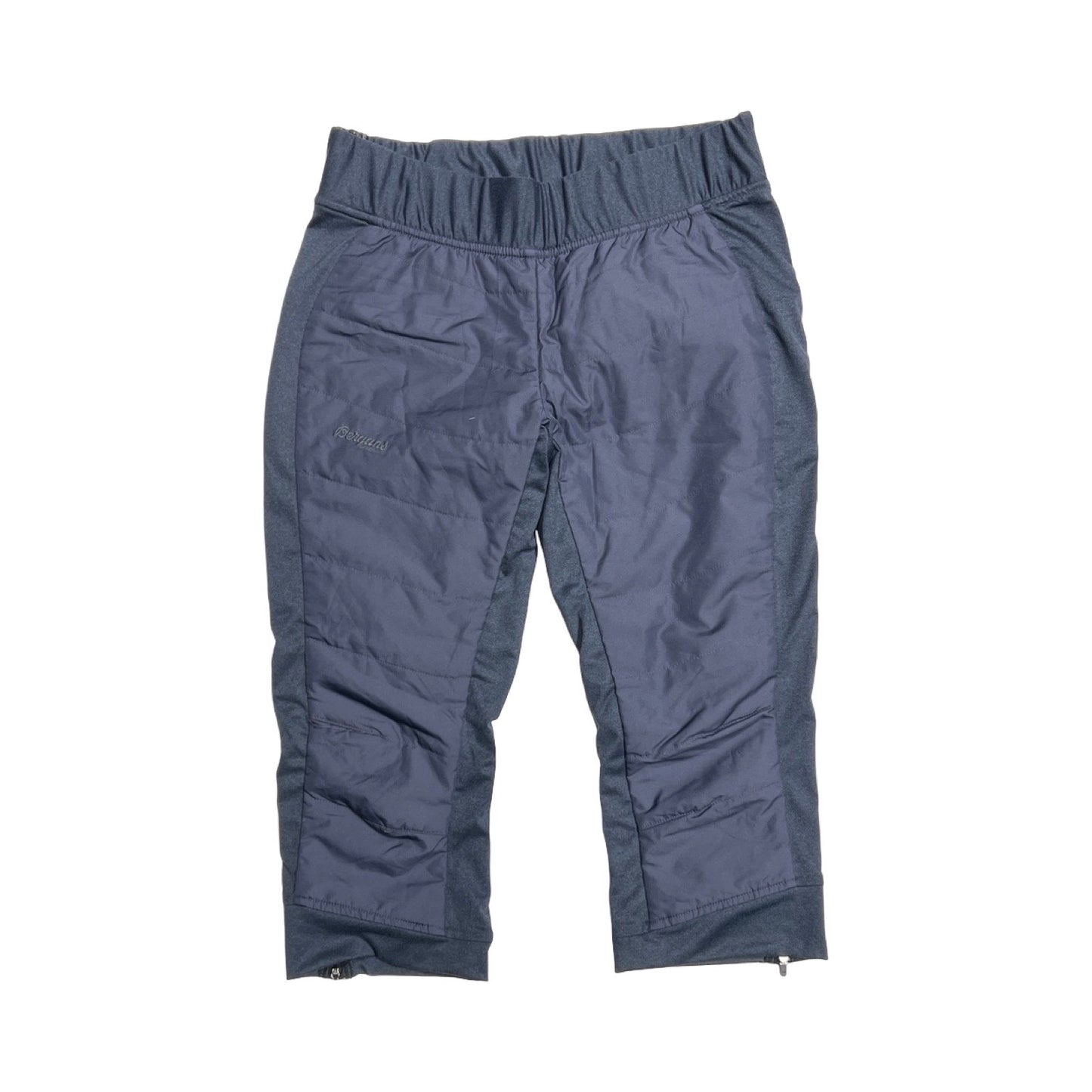 Bergans Stranda Hybrid 3/4 funktionsbyxa för dam i blått. Byxan är fotograferad platt framifrån mot en vit bakgrund.