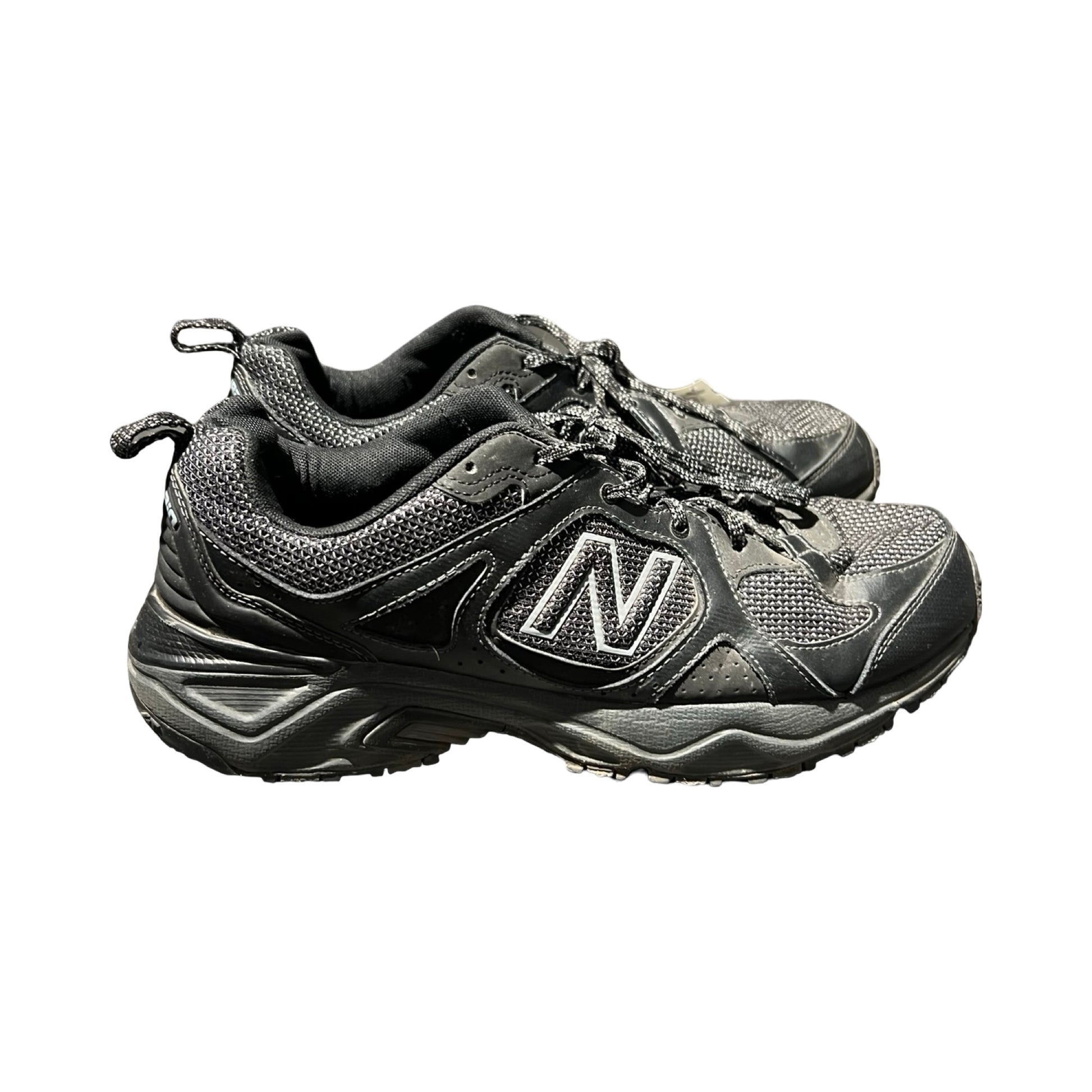 Ett par svarta löparskor för herr från New Balance, fotograferade från sidan mot en vit bakgrund.