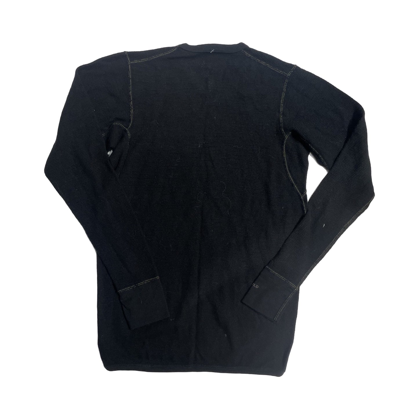 Baksidan av Devold underställströja för dam i svart, fotograferad utlagd platt mot en vit bakgrund.