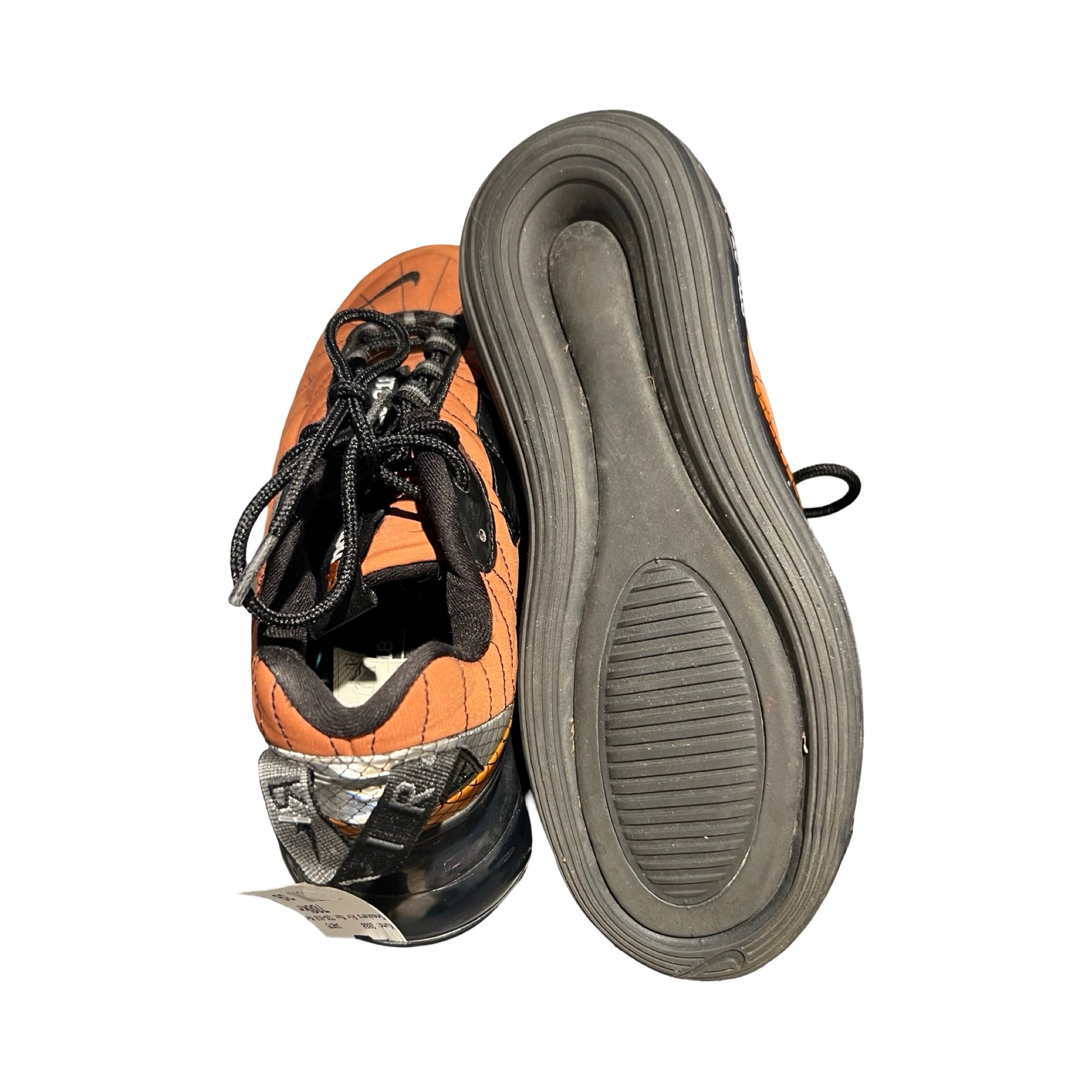 Ett par Nike Air Max 720-818 sneakers för dam i metallic copper och svart, fotograferade mot en vit bakgrund med fokus på sulan på ena skon.