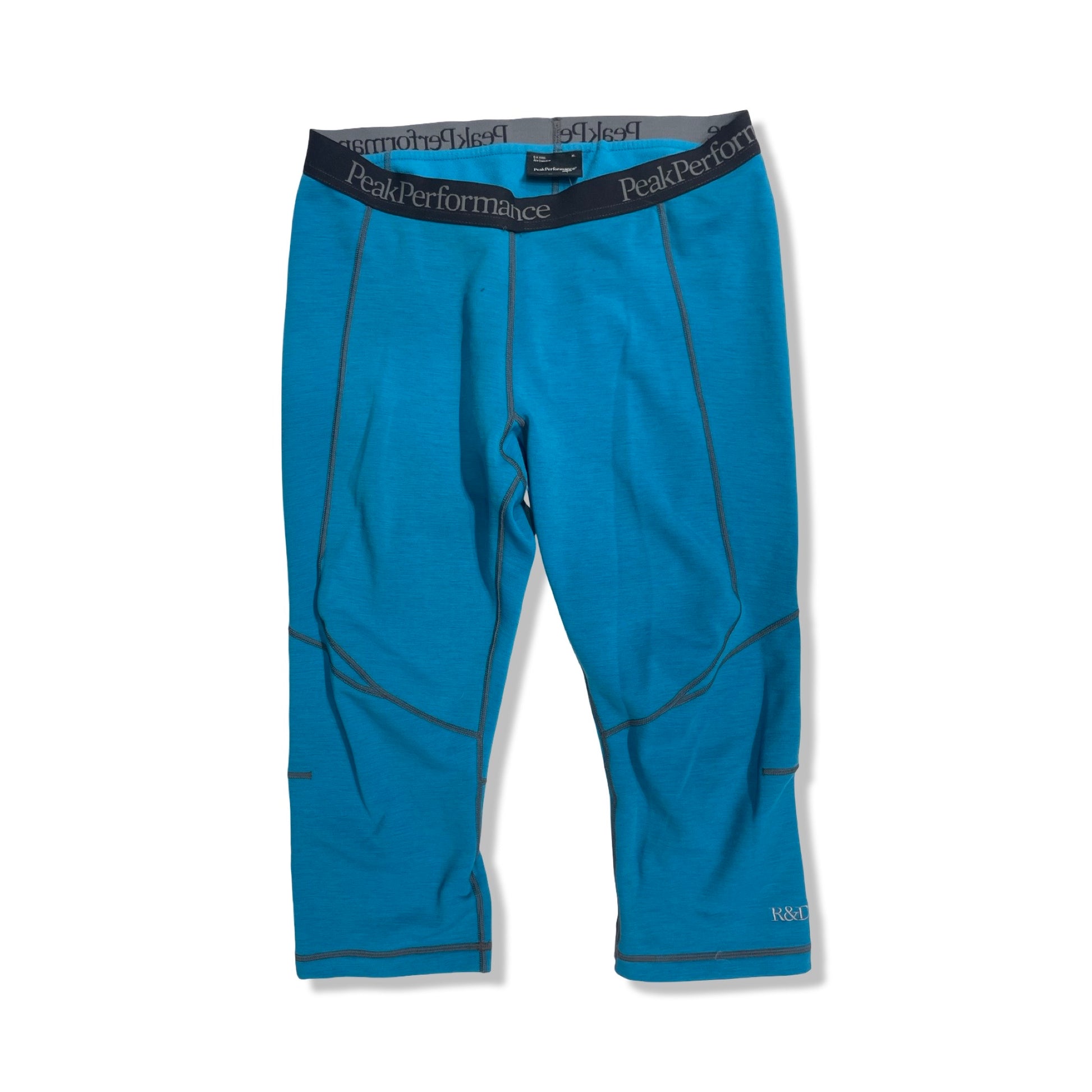 Peak Performance Heli Mid Tights underställsbyxor för herr i blått, fotograferade framifrån mot en vit bakgrund.