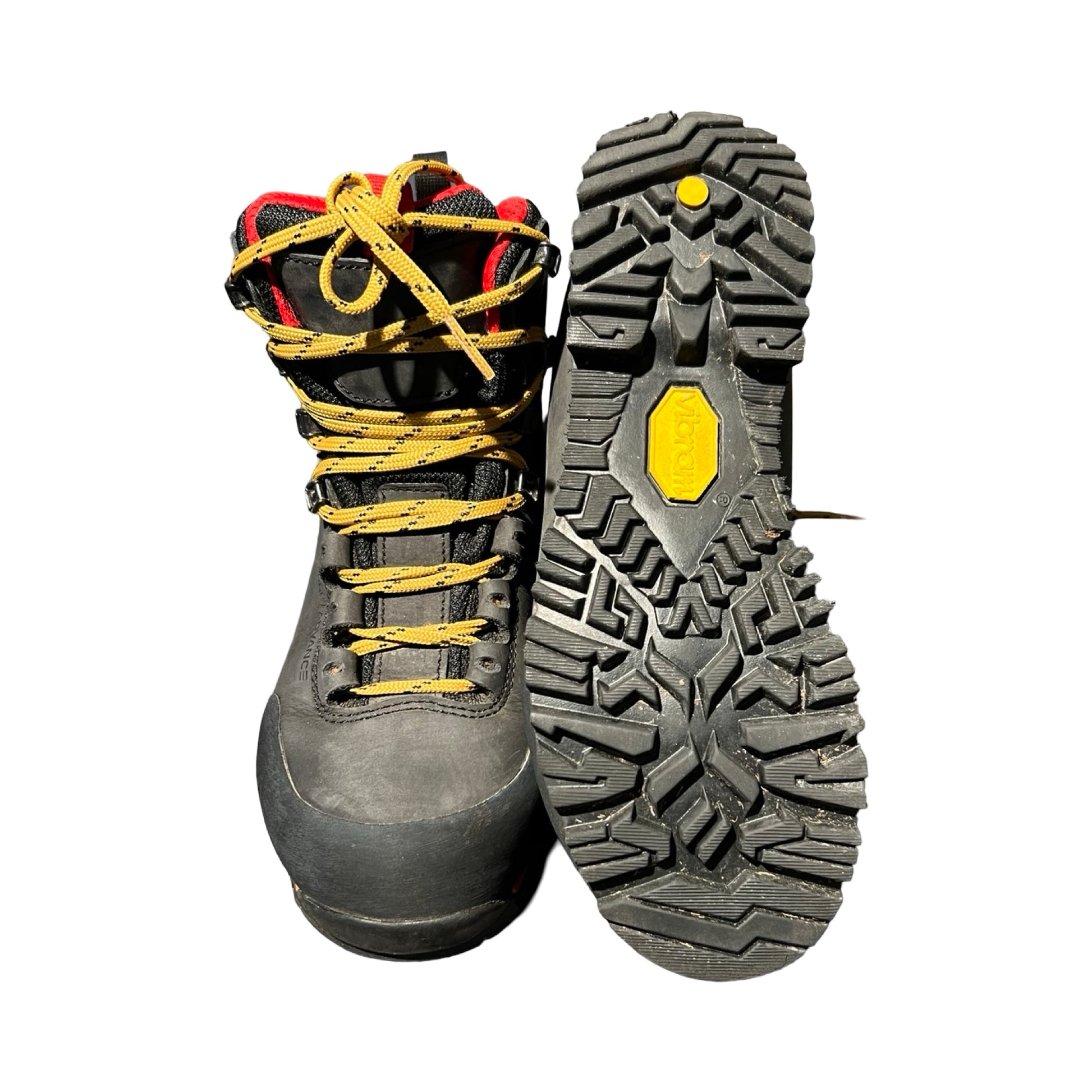 Alfa Eggi vandringskängor för dam i svart med gula skosnören och röda detaljer. Bilden visar en känga framifrån och den andra kängans Vibram-sula, fotograferade mot en vit bakgrund.