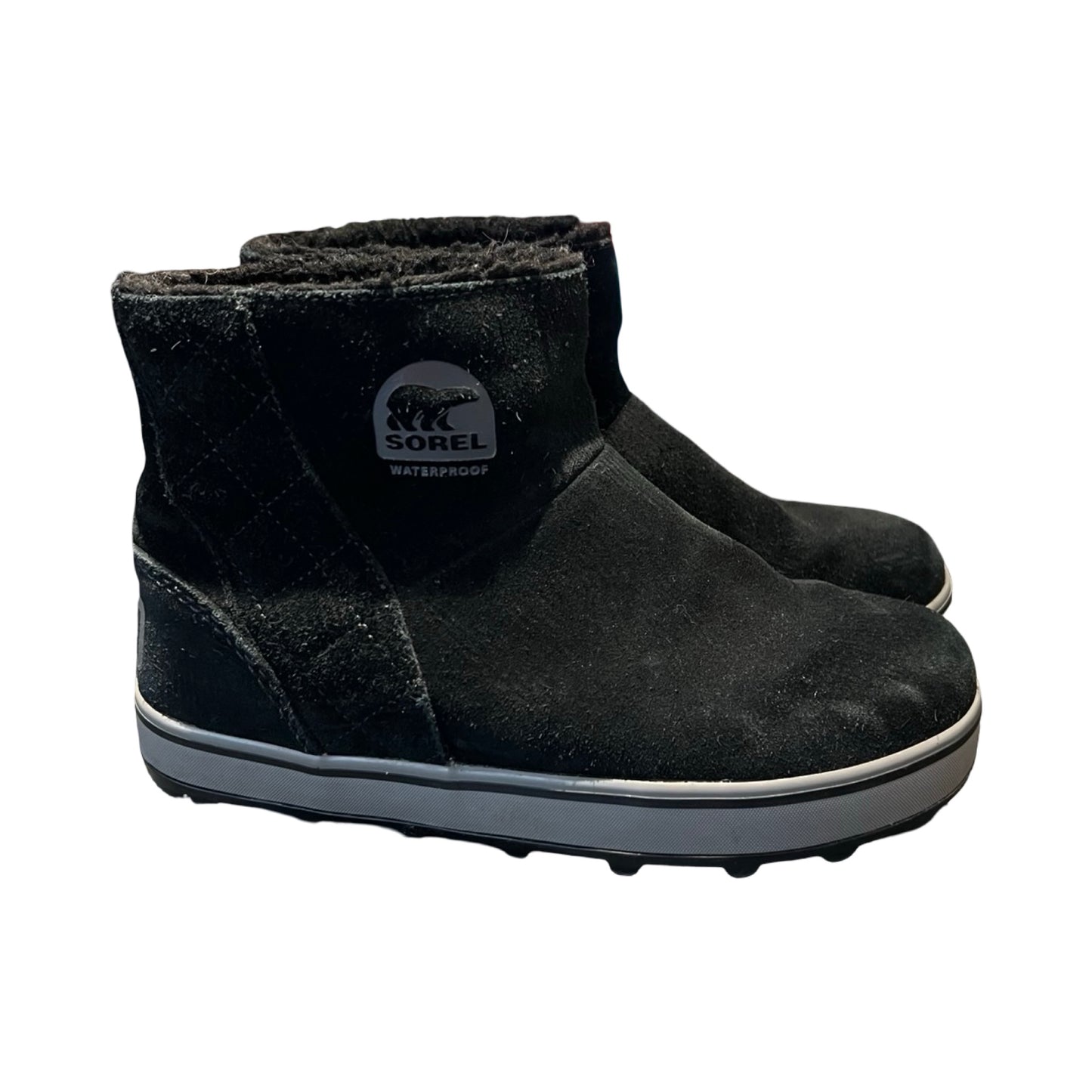 Svarta Sorel Wafterproof vinterkängor för dam i mocka med vit sula. Kängorna är fotograferade från sidan mot en vit bakgrund.