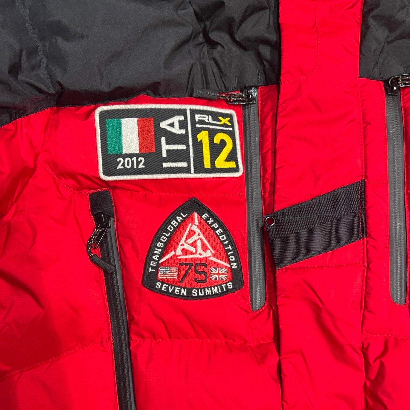 Närbild på detaljerna på bröstet av en Parkas RLX Transglobal Expedition för herr i rött och svart.