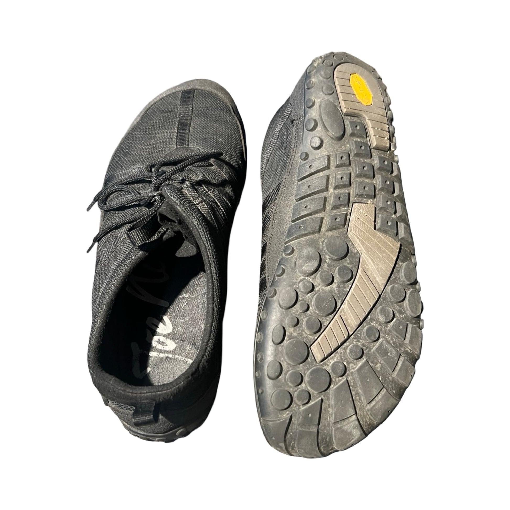 Ett par svarta Joe Nimble Nimble vandringsskor för herr. Bilden visar ena skon ovanifrån bredvid den andra skons sula, fotograferat mot en vit bakgrund.