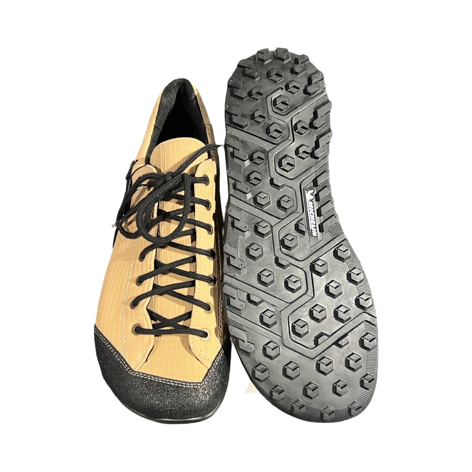 Joe Nimble TrekToes vandringsskor för herr i ökenfärg med svarta detaljer. Bilden visar en sko från ovansidan och den andra skons svarta sula, fotograferad mot en vit bakgrund.