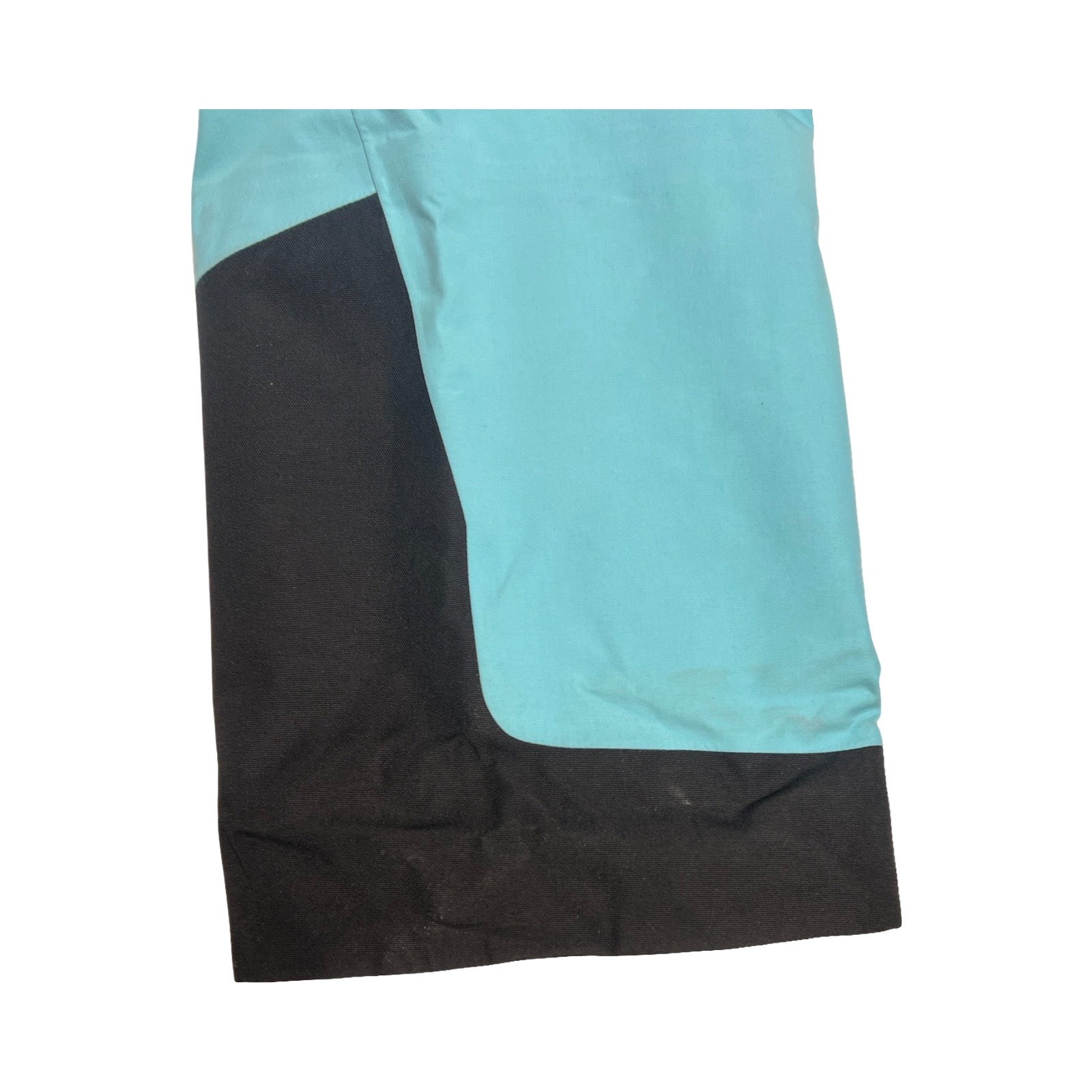 Detaljbild av fläckar på benslutet på Peak Performance GTX Pro skalbyxa för dam i ljusblått och svart.