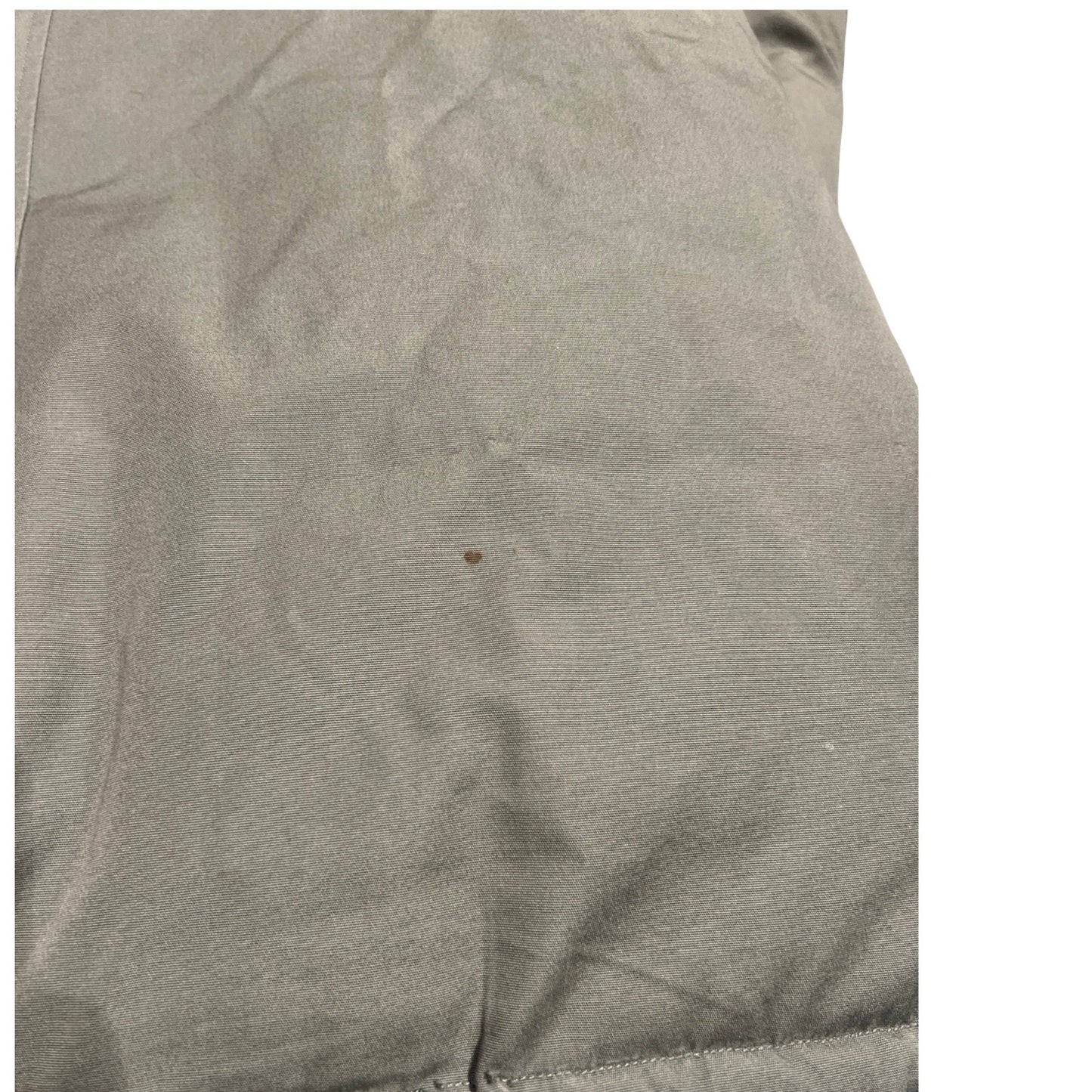 Närbild som visar en fläck på Peak Performance Down Parka dunjacka för dam i grönt.