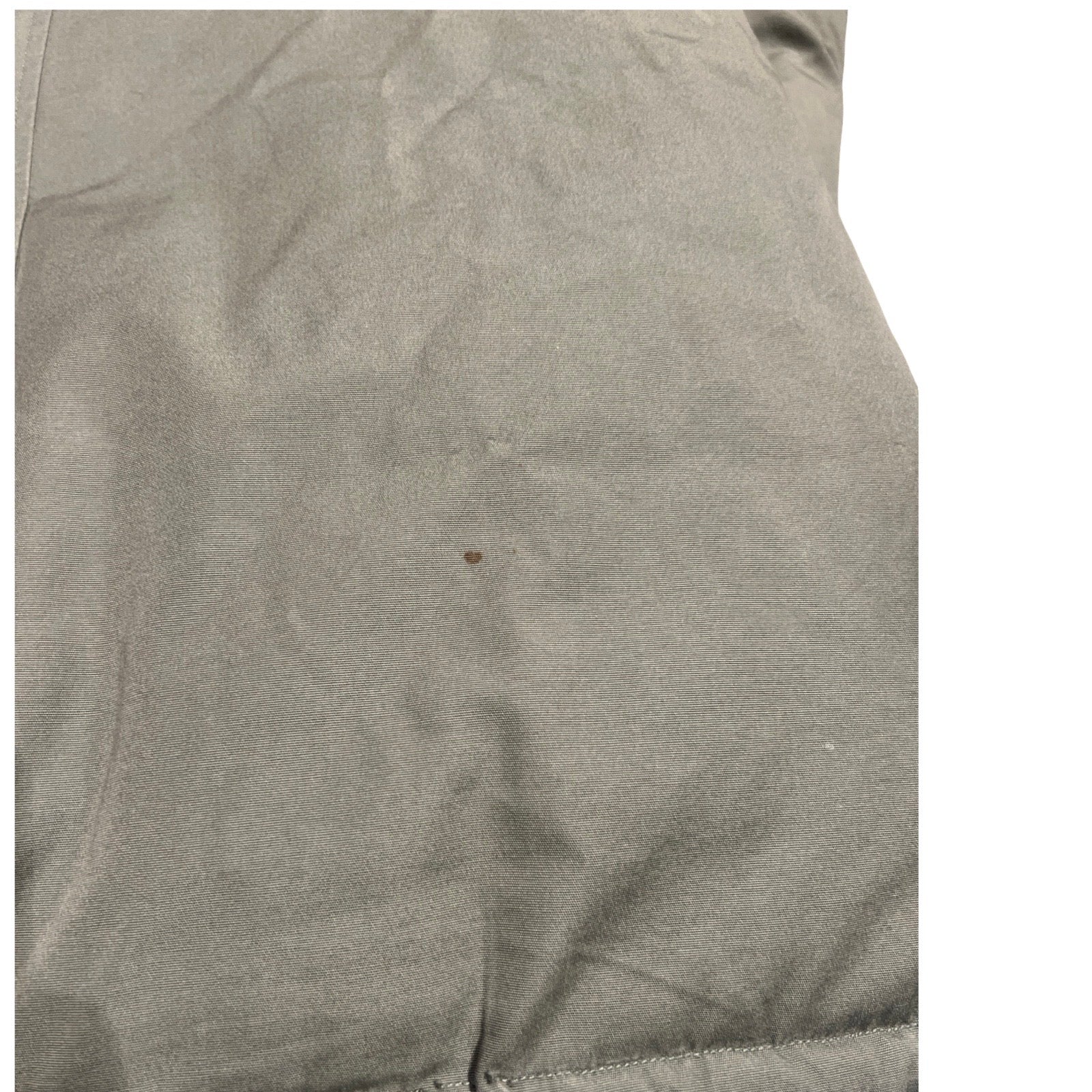 Närbild som visar en fläck på Peak Performance Down Parka dunjacka för dam i grönt.